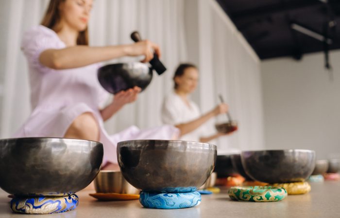 Two female yoga teachers play on Tibetan bowls in the gym during a yoga retreat.
